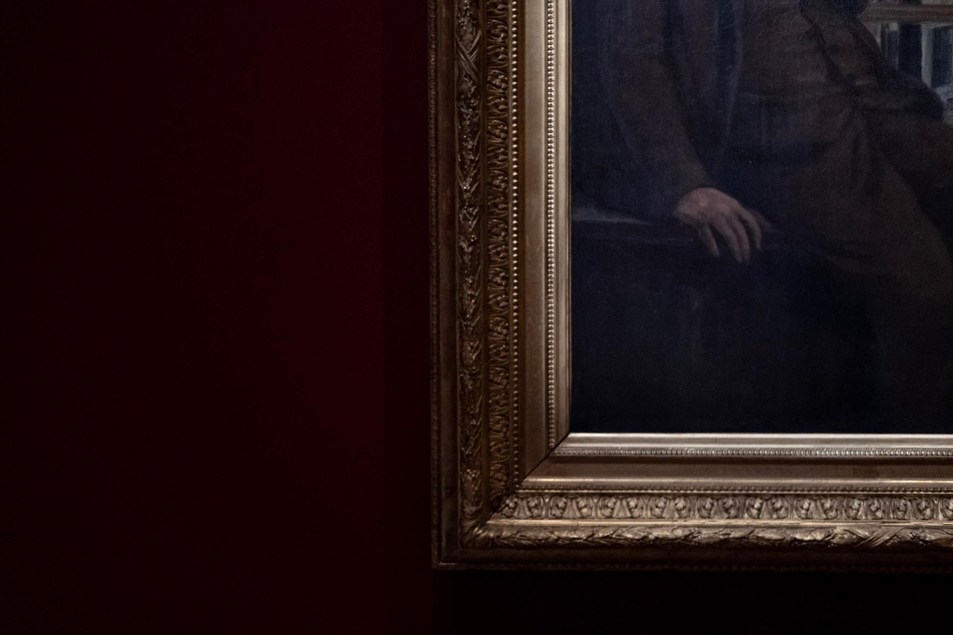 Detail of a gilded frame holding a dark classical painting